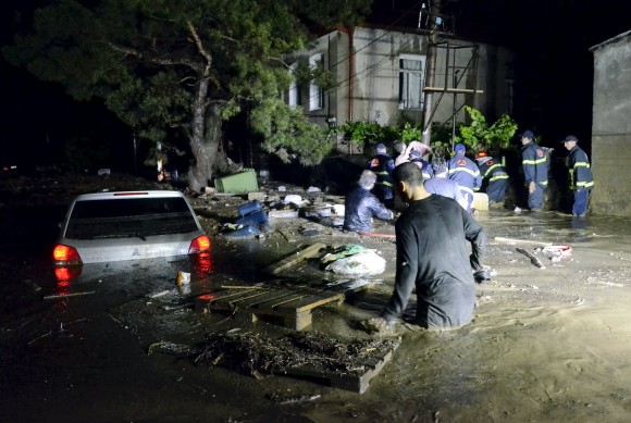 Local residents and rescuers wade at a flooded street in Tbilisi